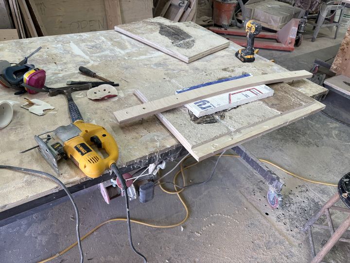 A workshop bench with a jigsaw, impact driver, rock hammer and chisels, and limestone plates laid out with wooden battens as cutting guides